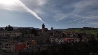 Belforte del Chienti 'nin büyüleyici hava manzarası, İtalya' nın orta kesimindeki berrak bir bahar gökyüzünün altında taş binalar, kuleler ve çevresindeki yemyeşil tepeler sergileniyor.