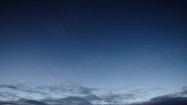 Geniş açılı bir zaman dilimi videosu, bulutların gün ışığından alacakaranlık gökyüzüne kademeli hareketlerini görüntüler, bulutların dinamik ve dinamik doğasını gerçek zamanlı olarak gösterir..