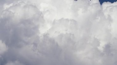 Kümülüs bulutlarının hareketli ve değişken hızlandırılmış büyüleyici görüntüsü, açık mavi gökyüzünde sürüklenirken dokularını vurguluyor, doğanın dinamik güzelliğini gösteriyor.