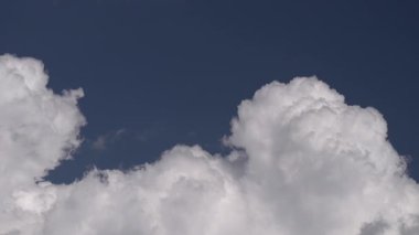 Yumuşak kümülüs bulutlarının büyüleyici hareketlerini ve evrimleşen dokusunu yakalayan hızlandırılmış video açık mavi gökyüzünde sürükleniyor ve dönüşüyor.