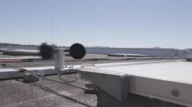 Rüzgar hızı sensörü ve endüstriyel bir çatıya monte edilmiş bir havalandırma sisteminin parçası. Görüntü, gerçek zamanlı çevresel izleme ekipmanlarını gösteriyor