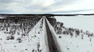 Hava aracı görüntüleri, karla kaplı bir İskandinav yolu boyunca gerçek zamanlı hareket ve manzara gösteren bir minibüs görüntüsü yakalıyor..