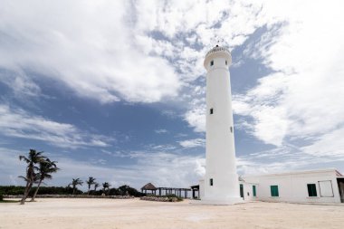 Cozumel Adası, Meksika 'daki ikonik beyaz deniz fenerini çeken çarpıcı bir görüntü. Bu fotoğrafta deniz feneri dramatik bulutların arka planında duruyor. Zarafetini ve Karayip ayipleri 'nin durağanlığını vurguluyor..
