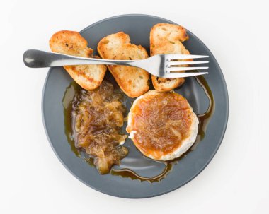 Lezzetli bir aşçılık sunumu. Üstünde karamelli soğan ve keçi peynirli dürüm var. Pürüzsüz, siyah bir tabakta altın tost, gurme yemeği için mükemmel.