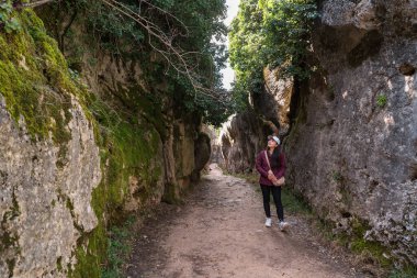 Genç bir Asyalı kadın La Ciudad Encantada, Cuenca, Castilla-La Mancha, İspanya 'da eşsiz kaya oluşumları arasında manzaralı bir yürüyüş yapıyor..