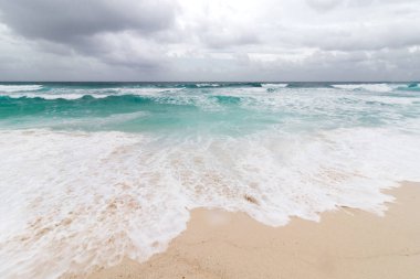 Cozumel, Meksika 'da berrak turkuaz suların ve beyaz kumlu plajların güzel ve sakin manzarası. Karayip Denizi üzerinde bulutlu bir gökyüzü.