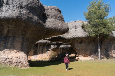 La Ciudad Encantada, Cuenca, Castilla-La Mancha, İspanya 'da yürüyen genç Asyalı kadın, açık mavi gökyüzü altında eşsiz kaya oluşumlarıyla çevrelenmiş..