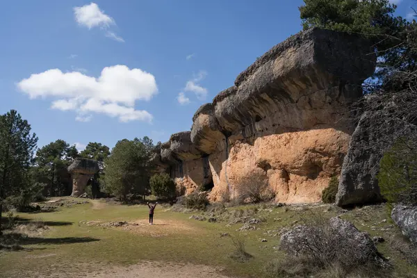 Uzak bir mesafede, kolları neşe içinde büyüyen tanınmayan Asyalı genç bir kadın La Ciudad Encantada, Cuenca, İspanya 'nın eşsiz kaya oluşumları arasında duruyor..