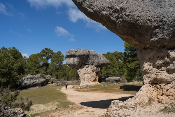 Uzak bir mesafede tanınmayan bir kadın doğal güzellik ve kültürel keşiflerin bir karışımını sergileyerek La Ciudad Encantada, Cuenca, Castilla-La Mancha, İspanya 'da eşsiz kaya oluşumları arasında tek başına yürüyor..