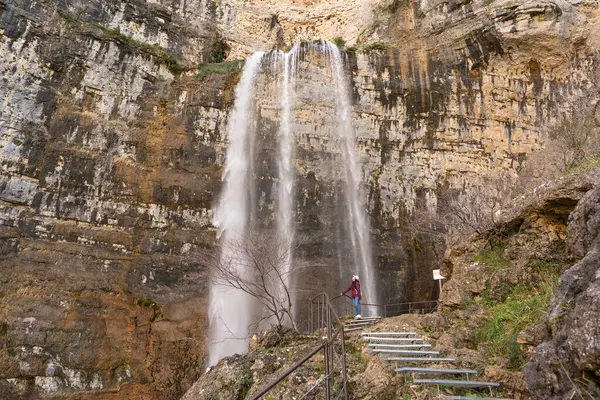 Genç bir Asyalı kadın Nacimiento Rio Mundo, Albacete, Castilla-La Mancha 'daki görkemli şelalenin yanında duruyor, doğanın güzelliğini takdir ediyor..
