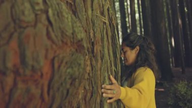 Avustralya, Büyük Okyanus Yolu 'ndaki Otway Sekoya Ormanı' nda bir kızılağaç ağacına nazikçe sarılıyor. Gözleri kapalı, kabuğun dokusuna bağlanır, ormanın enerjisini ve huzurunu hisseder.