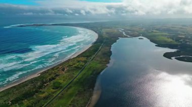 Victoria, Avustralya 'nın nefes kesici hava manzarası göz kamaştırıcı kıyı şeridini gösteriyor. Canlı mavi dalgalar, geniş bir gökyüzü altında, dağınık bulutlar altında yemyeşil ile buluşuyor..