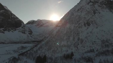 Norveç, Ersfjord 'un karla kaplı dağ zirvelerinde gün ışığı, bu nefes kesici manzaranın engebeli kış manzarasına huzur veren bir ışıltı saçıyor.