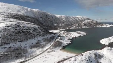 Norveç 'in Laukvikan Ranta kentindeki karla kaplı arazinin hava manzarası, kışın sakin denizi çevreleyen dağlık arazilerle sakin bir kıyı bölgesini gösteriyor.