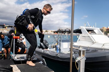 Scuba dalgıcı denizde dalış seansından sonra bir tekneden iniyor.