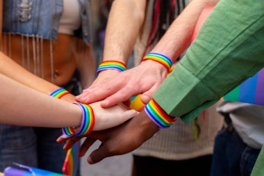 Gökkuşağı bileziği takan aktivistlerin elleri, bir gurur etkinliği sırasında birlik ve lgbtq artı haklar sembolize ediyor