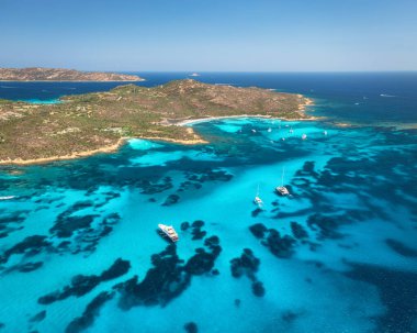 Lüks yatların ve mavi denizdeki teknelerin havadan görünüşü yaz güneşli günlerinde güzel bir ada. Kumsal, kayalık deniz kıyısı, Sardinya, İtalya 'da şeffaf turkuaz su. Üst dron görüntüsü. Deniz kenarında. Seyahat
