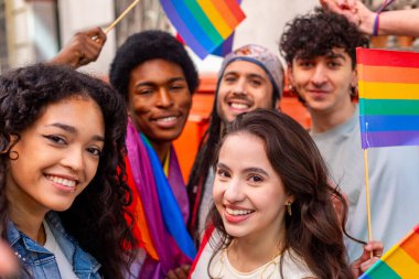 Gurur geçidinde gökkuşağı bayrakları sallayan mutlu çoklu etnik aktivistler, çeşitliliği ve lgbtq artı hakları kutluyorlar.