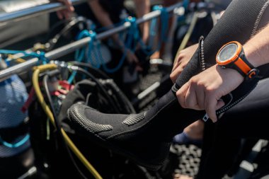 Dalgıç dalış botları giyer ve dalış bilgisayarı takar, bir tekneden dalışa hazırlanır.