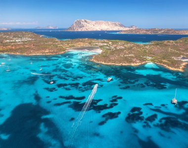 Lüks yatların ve mavi denizdeki teknelerin havadan görünüşü yaz güneşli günlerinde güzel bir ada. Kumsal, kayalık deniz kıyısı, Sardinya, İtalya 'da şeffaf turkuaz su. Üst dron görüntüsü. Deniz kenarında. Seyahat
