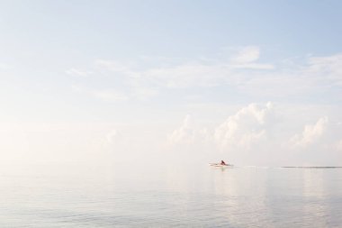 Tanınmaz haldeki Filipinli küçük katamaran üzerinde güneş doğarken yüksek hızda denizi geçiyor gökyüzünden ayırt edilemeyen su, Anda Sahili, Bohol
