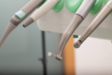 Yaklaşan hasta ziyareti için hazırlanmış, iyi donanımlı bir dişçi kliniğinde asılı modern diş aletlerine yakından bakın