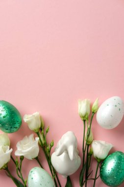 Paskalya düzlüğü kompozisyonu. Pastel benekli yumurtalar, beyaz çiçekler ve yumuşak pembe arka planda seramik bir tavşan.