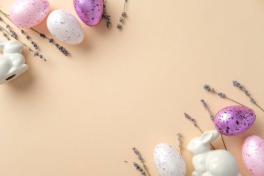 Paskalya düzlüklerinde benekli yumurtalar, seramik tavşancık heykelcikler ve bej arkaplanda lavanta filizleri vardı..