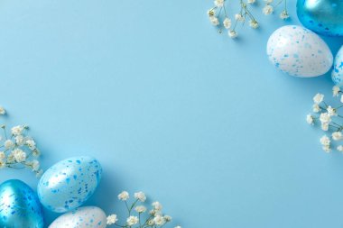 Pastel Paskalya sahnesi açık mavi arka planda benekli mavi ve beyaz yumurtalar ve küçük beyaz çiçekler..