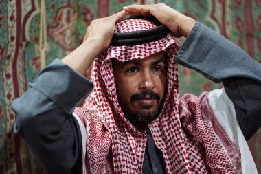 Geleneksel başörtüsü takan Bedevi adam Suudi Çölü, Suudi Arabistan 'daki akıllı telefonuna bakıyor.