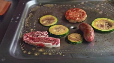 Bir barbekü tabağında kuzu pirzolası, sosis ve kabak ızgarası olan, çeşitli lezzet ve dokular sunan klasik bir Avustralya barbeküsünün canlı bir gösterisi.