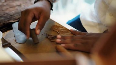 Yetenekli eller, doğal yapraklarla sigara yapma sürecini titizlikle bitirir. Meksika 'daki bir atölyede geleneksel zanaatkarlığın özünü yakalar. Zamansız bir sanat türünün yakın çekimi.