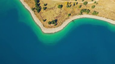 Yeni Zelanda Canterbury bölgesindeki Tekapo Gölü 'nün nefes kesici manzarası. Görüntü gölün canlı turkuaz sularını yakalıyor. Topraksı kıyı şeridiyle çelişiyor..