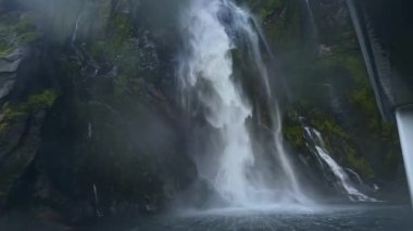 Milford Sound, Yeni Zelanda 'nın kayalık yeşil uçurumlarından suyla kaplı görkemli şelaleler. Yeşil arazi büyüleyici bir doğa sahnesi yaratır.