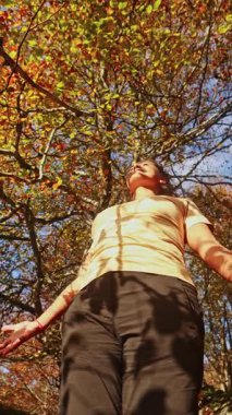 Bir kadın, Bask Bölgesi 'ndeki Gorbea Doğal Parkı' nda yürürken sonbaharın güzelliğini kucaklıyor. Canlı yeşilliklerle çevrili, sakin açık hava deneyimini seviyor.