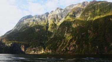 Yeni Zelanda 'daki Milford Sound' un çarpıcı manzarası, yükselen uçurumlar ve gür gökyüzü altında yemyeşil, doğanın el değmemiş güzelliğini ve ihtişamını yansıtıyor.