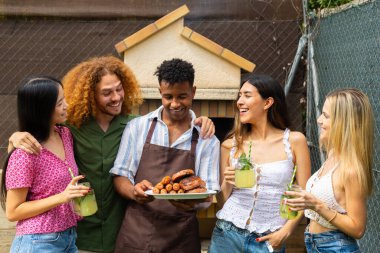 Mutlu arkadaşlar arka bahçedeki barbekü partisinde güler ve ızgara yemekten ve taze içeceklerden zevk alırlar.