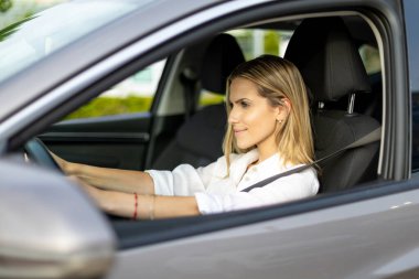 Şık, modern bir arabayla gezen genç bir iş kadını coşkulu şehirde mutluluk ve başarı hissi yayıyor.