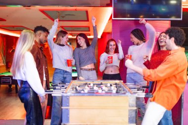 Bir grup neşeli çoklu etnik arkadaş bir barda langırt oynayıp içerken tezahürat yapıyorlar.