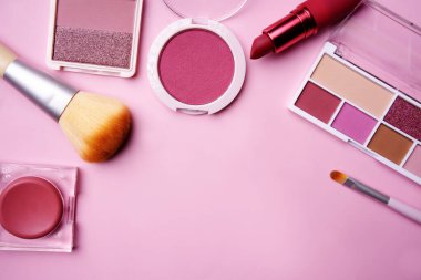 Pembe bir yüzeye yerleştirilmiş çeşitli pembe makyaj ürünleri, kopya alanı olan bir çerçeve oluşturur