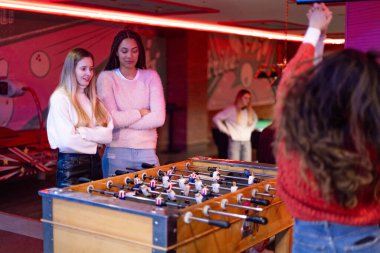 Canlı bir eğlence merkezinde langırt oynayan genç kadınlar boş zamanlarını ve rekabetlerini sergiliyorlar.