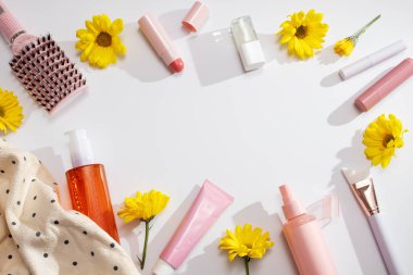 Güzellik ürünleri arka plan çerçevesi çiçek, cilt bakımı, saç bakımı ve makyaj malzemeleriyle bembeyaz arka plan gölgeler, bahar cilt bakımı, üst görünüm, kopyalama alanı ile yatıyordu