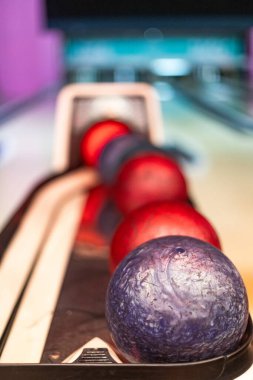 Bowling topları kullanılmayı bekliyor. Bowling salonundaki dönüş makinesinde dinleniyorlar. Eğlenceli bir etkinlik öneriyorlar.