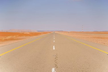 Suudi Arabistan 'da uzaklardan geçen kırmızı kum çölleriyle çevrili güzel düz bir otoyol.