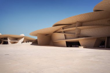 Ulusal Katar Müzesi 'nde çöl gülleri şeklinde binalar boyunca yürüyen tanınmayan ziyaretçiler.