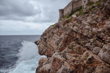 Dubrovnik 'in duvarları arka planda, Hırvatistan' ın dalgaları kayalara çarpıyor