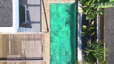 Turkuaz dikdörtgen bir havuz ve tropik bir tatil köyünde ahşap bir güverte.