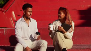 İki iş adamı, Melbourne 'un şehir merkezinin canlı kırmızı zeminine karşı kahve içerken canlı bir şekilde tartışıyorlar. Sahne, modern şehir iş hayatını yakalıyor.