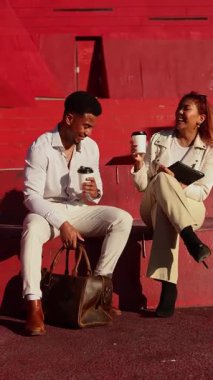 İki iş adamı Melbourne 'da bir kahve molasını paylaşıyor. Şehir merkezindeki basamaklarda oturuyorlar, sohbet ediyorlar, kentsel ve modern bir hava yayıyorlar.