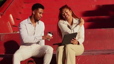 İki profesyonel, güneşli bir günde Melbourne, Avustralya 'da bir tablet kullanarak ve fikirlerini bir kahveyle paylaşarak canlı kırmızı adımlar üzerine ortak bir tartışmaya giriştiler.